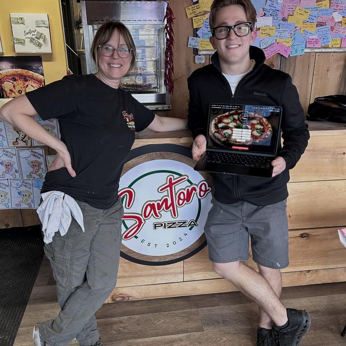 Adam with the owner of Santoro Pizza, showing their new website